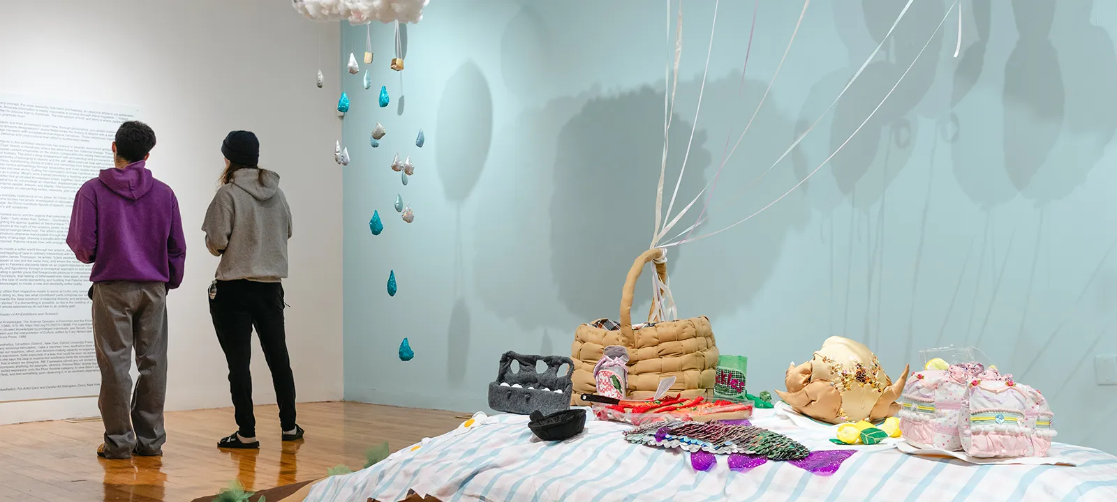 Two people take in an exhibit that includes a picnic scene.