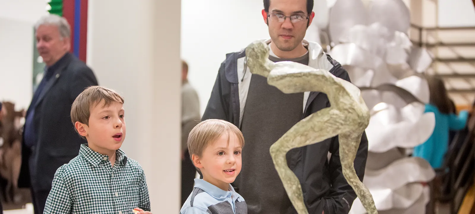 A parent and two kids take in a sculpture during an art opening.