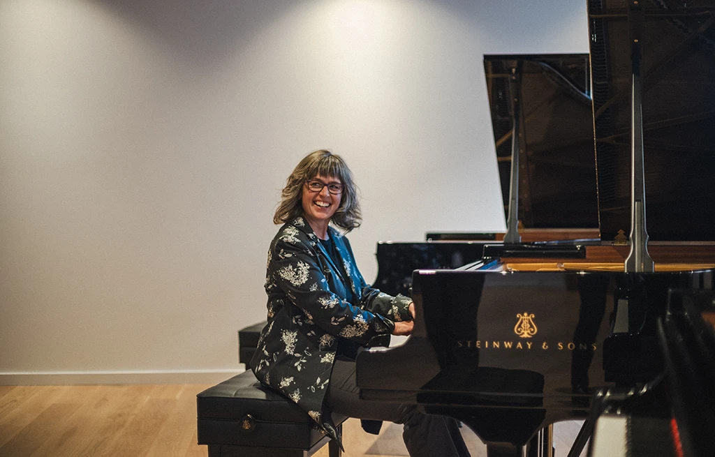 A university instructor seated at a Steinway piano.
