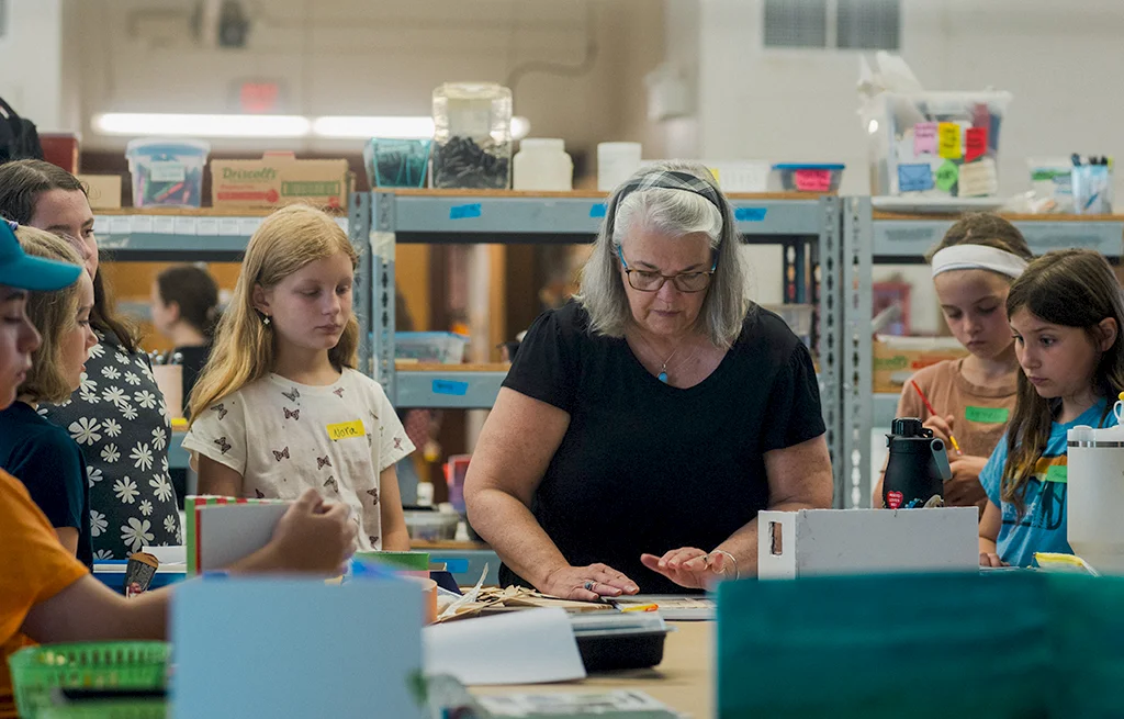 A woman works with kids on an art project.
