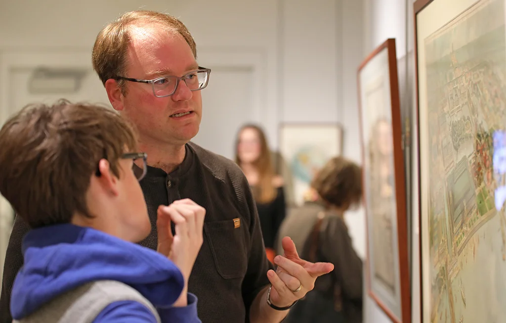 Two people examine a framed map on the wall during an exhibit.