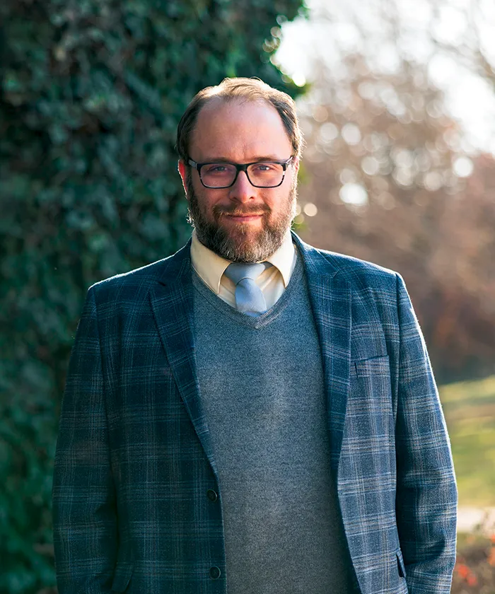 Dr. Kyle Nielsen outdoors wearing a plaid blazer and grey sweater.