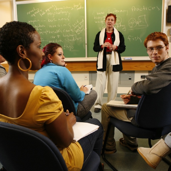 Students in class with teacher at the front of the room.