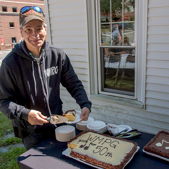 A community member poses for the camera with the first slice of sheet cake during the WMPG 50th celebration.