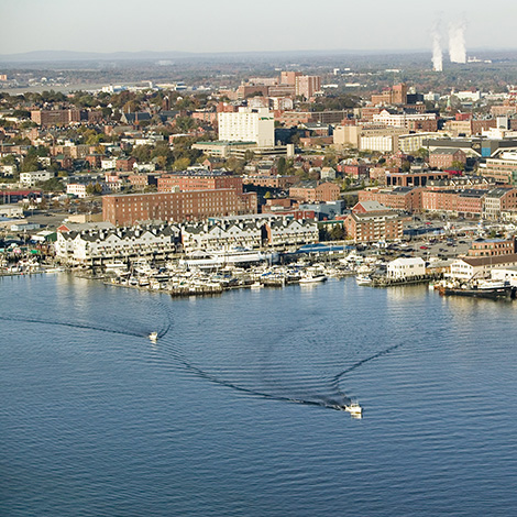 An aerial view of Portland Harbor. Two boats are moving through the water and tugboats can be seen on the right.