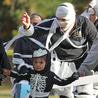 Kendall Migliorini gets a trick-or-treater ready to run an obstacle course at the Husky Community Howl-o-Ween Party.