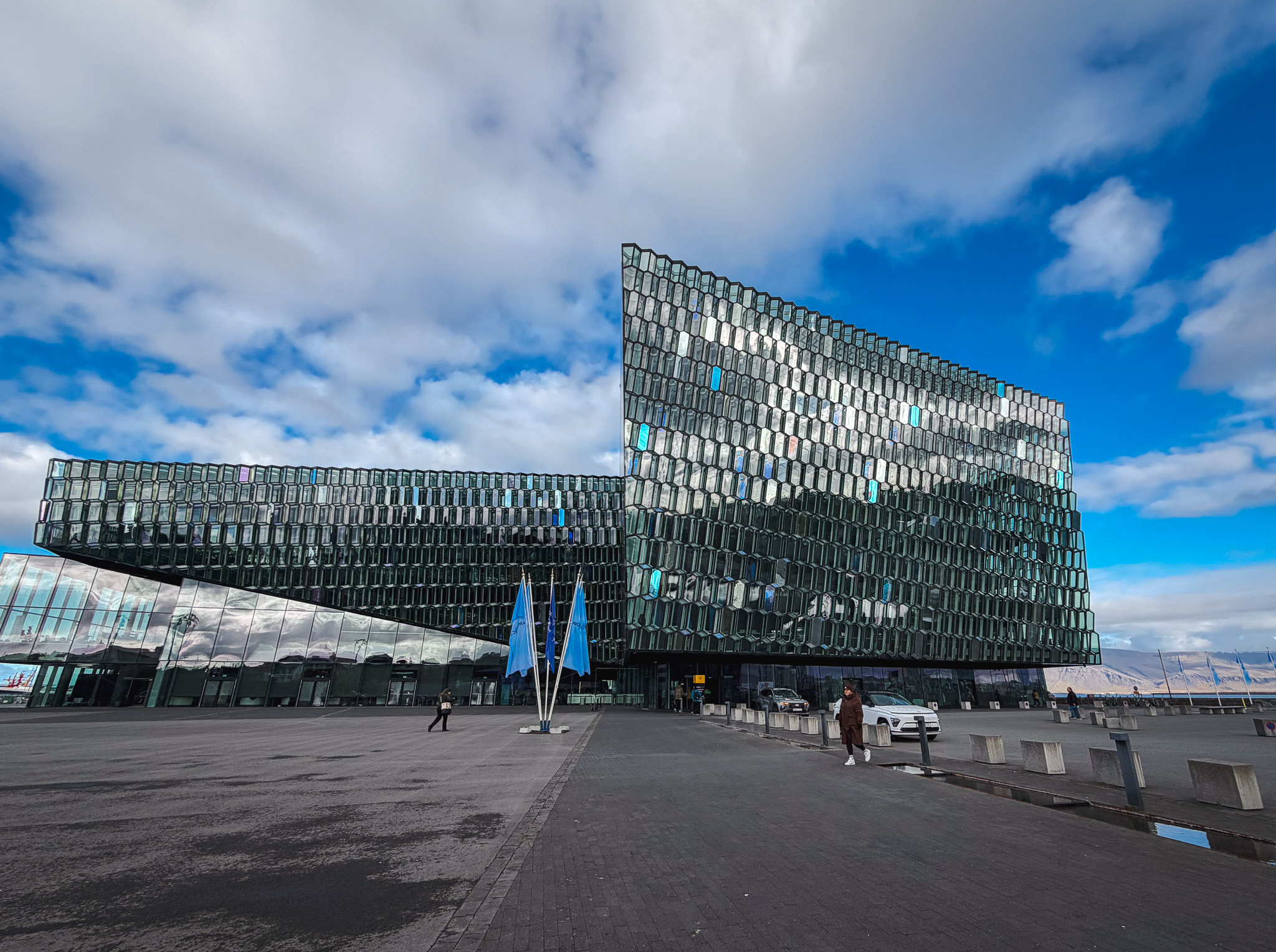 The glass exterior of Harpa in Reykjavik, Iceland, the venue for the Arctic Circle Assembly, with blue flags out front.