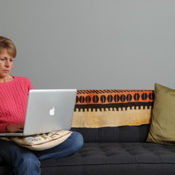 Person sits on a couch with a computer in their lap