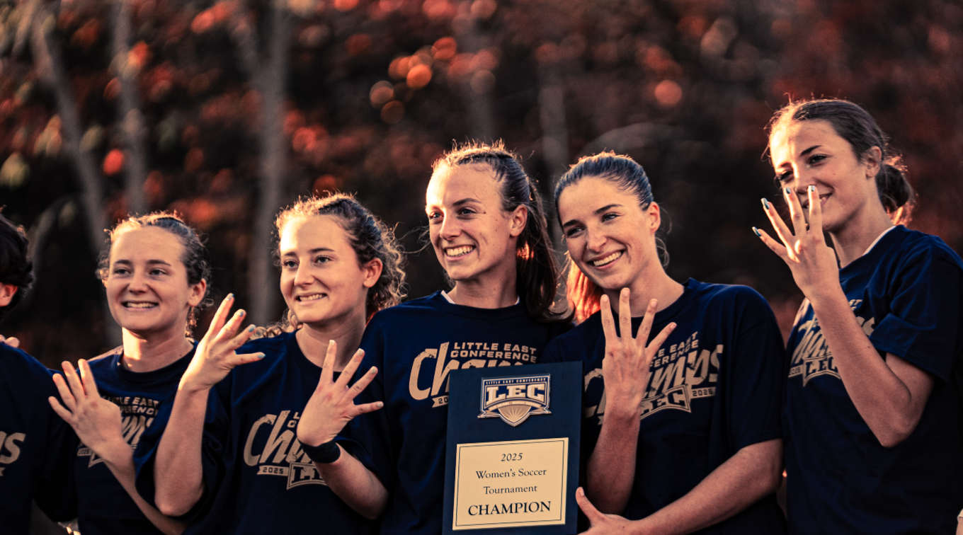 USM women’s soccer seniors smiling and holding up four fingers to celebrate their Little East Conference win.