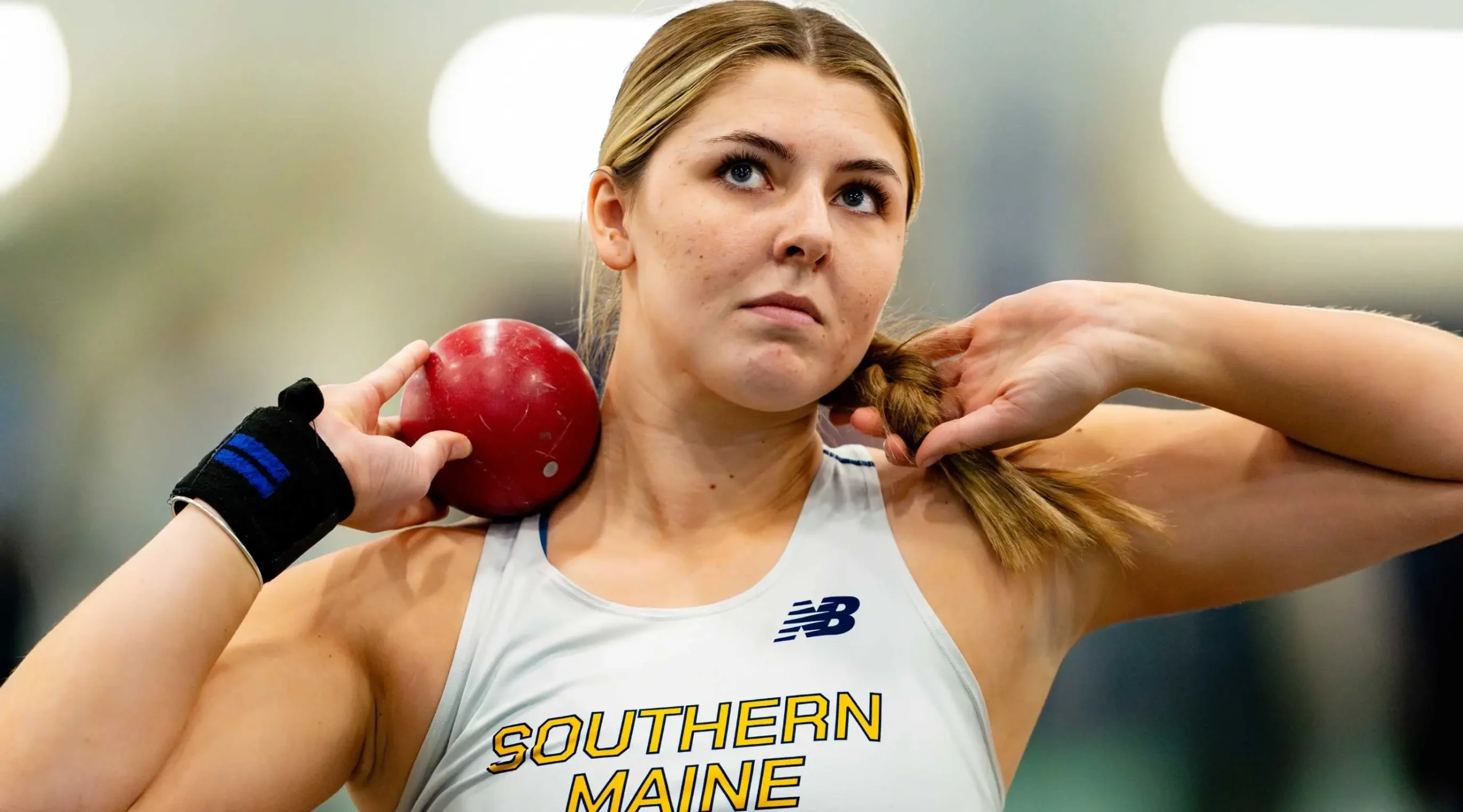 Zoe Barnes mentally preparing with shot put loaded on shoulder ahead of her heat.