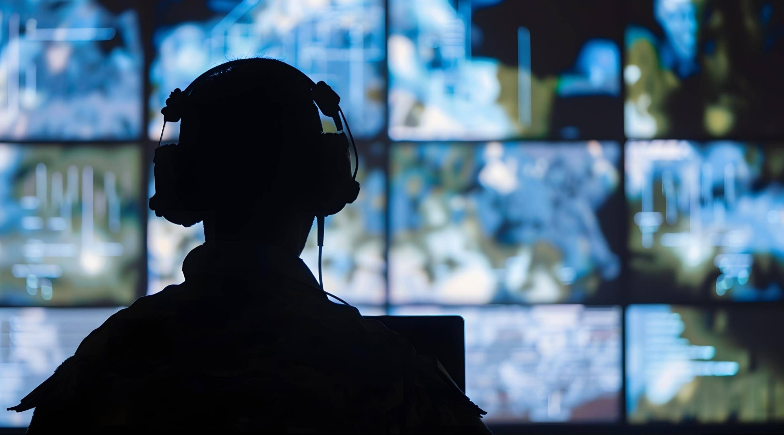 Stylistic image of a person wearing headphones watching multiple screens, mirroring CIA analyst activites.
